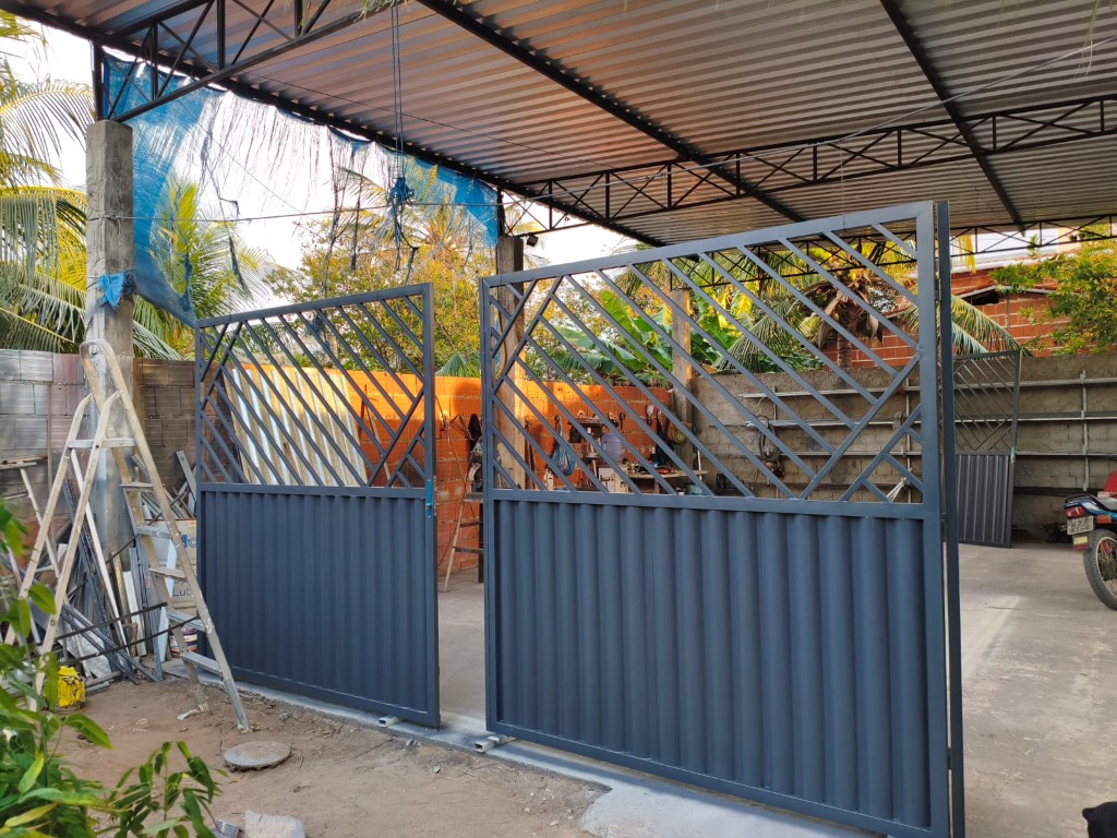 Portão metálico cinza com treliça diagonal e chapa ondulada, fabricado pela MetalúrgicaJB